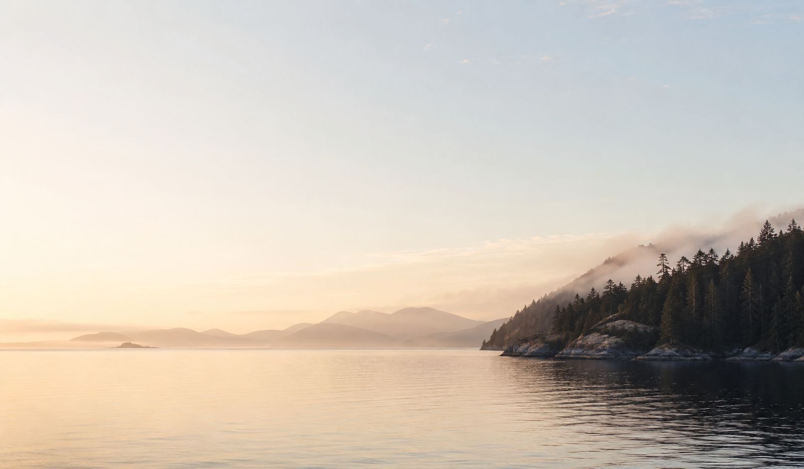 A calm early-morning coastline in British Columbia, soft light over still water
